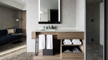 Un baño moderno con un espejo grande, un mueble de tocador de madera y una zona de ducha integrada.