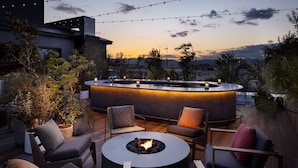 A modern outdoor seating area with a circular fire pit, lounge chairs, and ambient string lights. - Nohga Hotel Kiyomizu Kyoto (Kyoto)