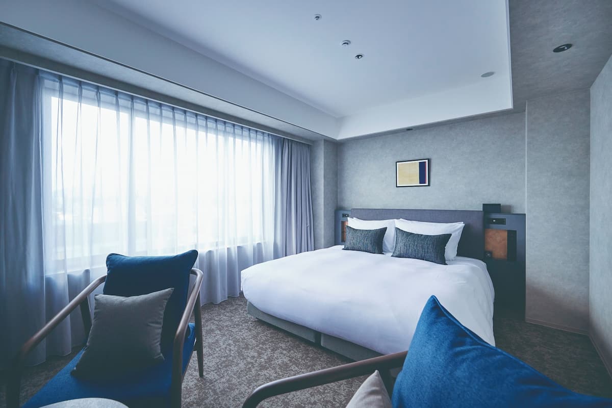 Une chambre d’hôtel moderne avec un grand lit, une chaise et une table de chevet.