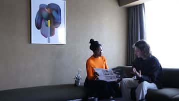 Two people sitting on a couch in a room with a large abstract painting on the wall.