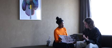 Two people sitting on a couch in a room with a large abstract painting on the wall.