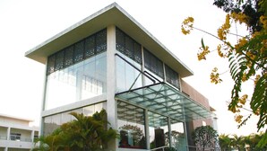 Un bâtiment moderne doté d’une façade en verre, d’une entrée abritée et d’un escalier menant à l’entrée.