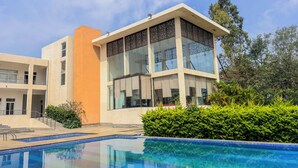 Un bâtiment moderne doté d’une façade en verre et d’une piscine à l’avant.