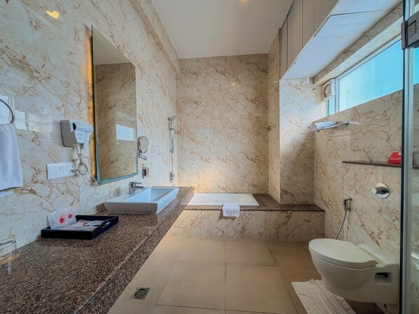 A modern bathroom with a marble wall, a sink, a toilet, and a shower.