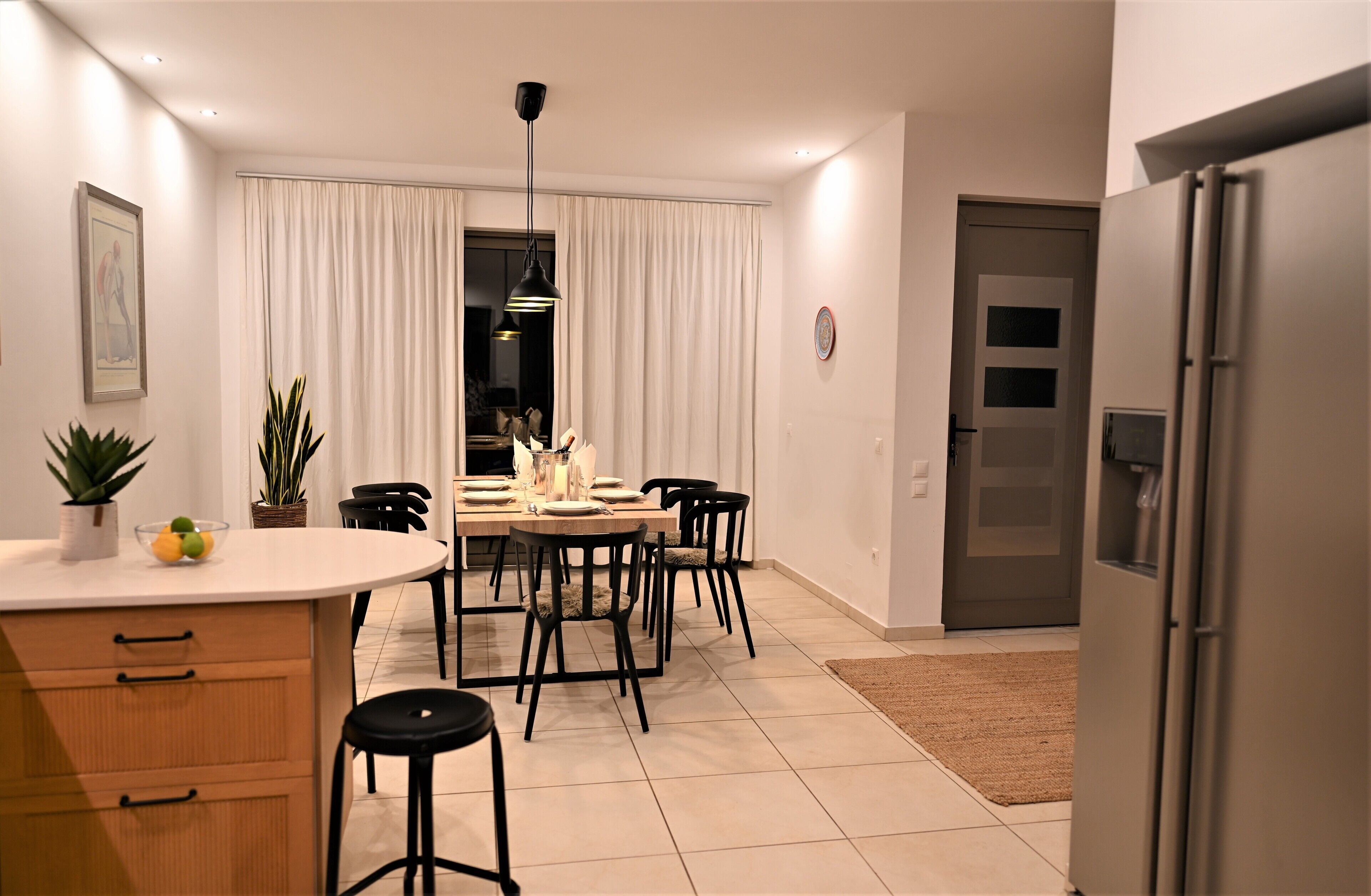 Une cuisine moderne dotée d’un espace repas, comprenant un grand îlot central avec un évier, un réfrigérateur et une table à manger avec des chaises.