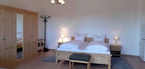 A bedroom with a bed, bedside tables, a wardrobe, a floor lamp, and a bench. - Apartment 7 equestrian facility - riding and holiday farm Blohm - object 26099 (Rostock)
