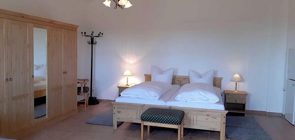 Ein Schlafzimmer mit Bett, Nachttischen, einem Kleiderschrank, einer Stehlampe und einer Bank.