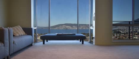 Une pièce dotée d’une grande porte-fenêtre coulissante donnant sur un balcon avec vue sur la ville.