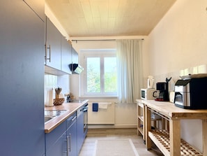 A compact kitchen with a window, a microwave, a coffee maker, and a sink.