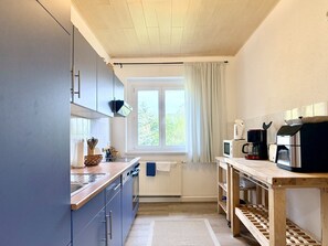 A compact kitchen with a window, a microwave, a coffee maker, and a sink.