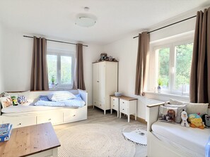 A cozy room with a sofa, a small table, a cabinet, and a window with curtains.