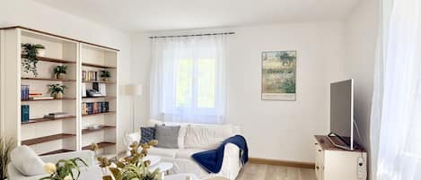 Una sala de estar moderna con un sofá, una mesa de centro, una estantería y un televisor.