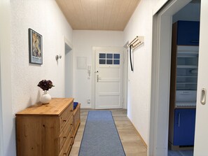 A hallway with a wooden dresser, a blue mat, a white door, and a blue cabinet.