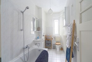 Un baño moderno con bañera, ducha, inodoro y lavamanos.