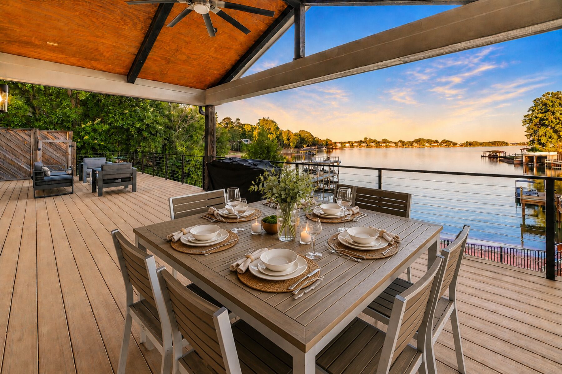 Un área de comedor al aire libre con una mesa dispuesta para seis personas, con vista a un lago.