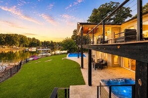 A modern house with a pool, a deck, and a view of a lake.