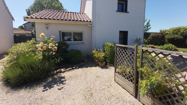 A two-story house with a tiled roof, a small front porch, and a gravel driveway. - In the city or in the countryside! 2.7 km from the Valentré Bridge (PRADINES)
