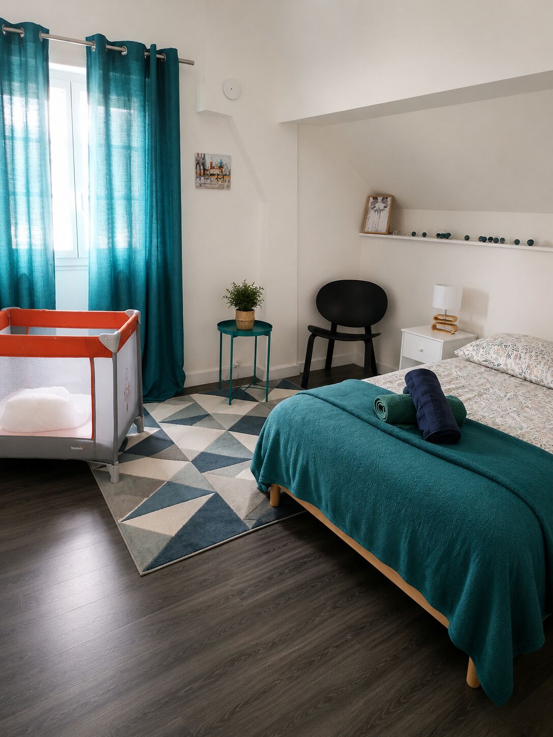 Un dormitorio moderno con cama, una mesita con planta, una silla y una mesita de noche.