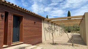 Un bâtiment moderne avec une porte en bois et un petit arbre devant.