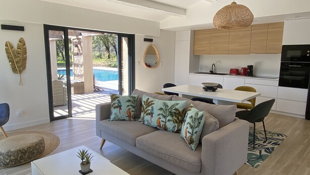 Un salon moderne avec un canapé, une table basse et une vue sur une piscine.