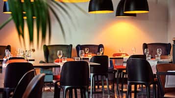 A restaurant with black chairs, tables, and hanging pendant lights.