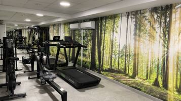 Ein Fitnessstudio mit Laufbändern, Crosstrainern und Krafttrainingsgeräten.