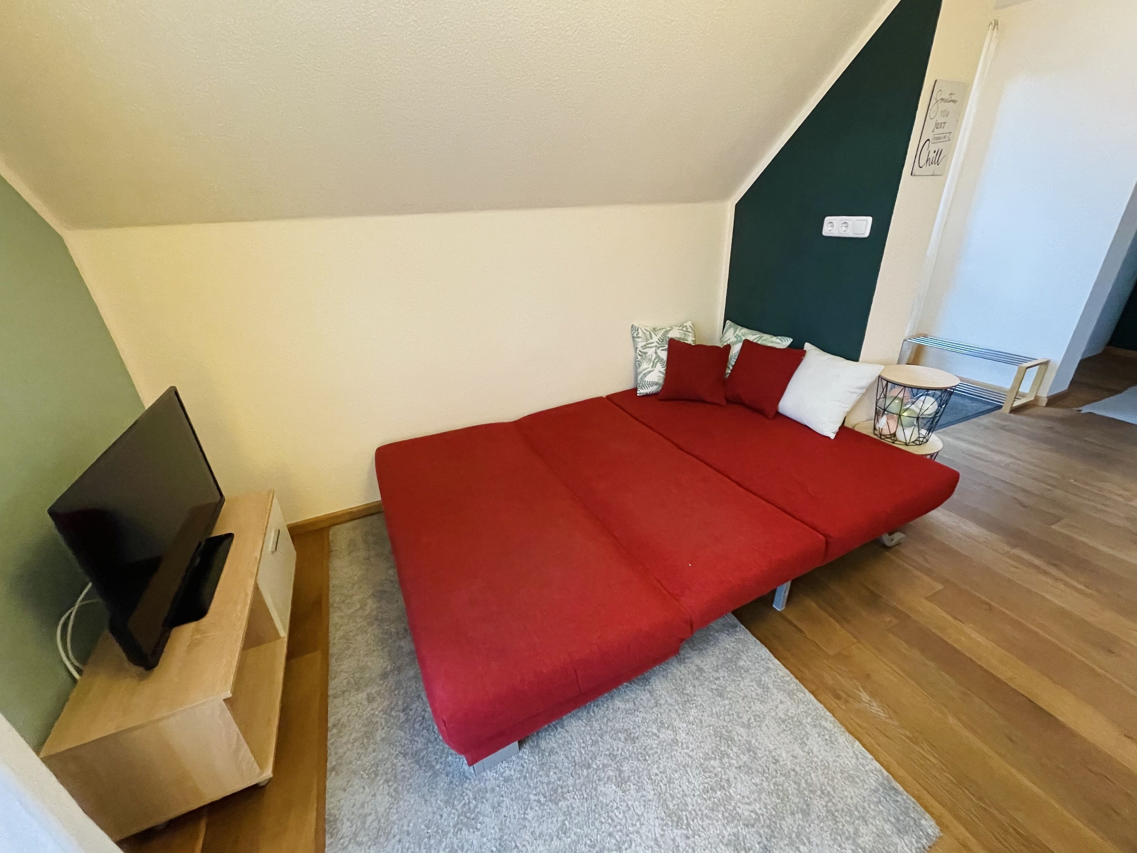 A room with a bed, a TV, a small table, and a radiator.