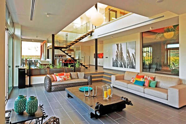 A spacious living area with a sofa, coffee table, and decorative items. A staircase leads to an upper level.