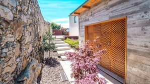Un muro de piedra, una cerca de madera y un edificio con techo inclinado.