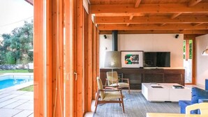 Un espacio al aire libre con piscina, techo de madera y mobiliario moderno.