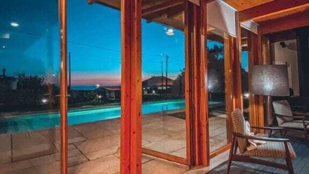 Un interior moderno con piscina, vigas de madera y vistas al exterior.