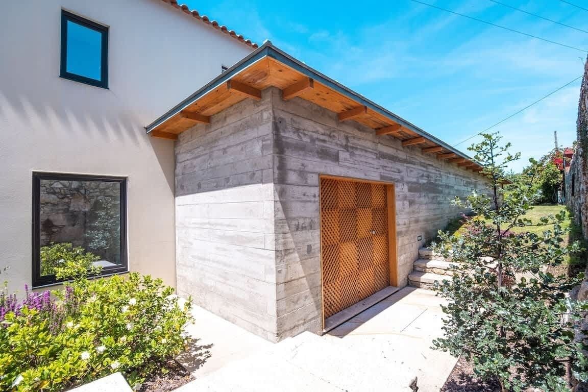 Un bâtiment moderne avec une façade en pierre, une porte en bois et une petite fenêtre.