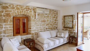 A living room with a stone wall, a wooden cabinet with glass doors, a white sofa, and a small wooden table.