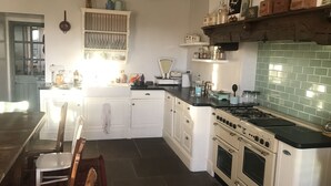 A kitchen with white cabinets, a stove, and a sink. There are various kitchen items on the countertops.