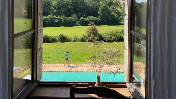 A room with a large window overlooking a garden and a swimming pool.