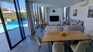A modern living room with a large TV, a sofa, and a dining table with fruit.