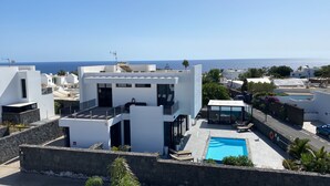 A modern building with a rooftop pool and a clear view of the sea.