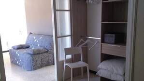 Une chambre à coucher avec un lit, une chaise, une armoire et une petite table.
