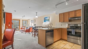 A modern kitchen with wooden cabinets, stainless steel appliances, and a central island with a dishwasher. - C303 Peaceful Canmore Corner- Downtown, Free parking, View, 2BR, 2BT, Sleeps 7 (Canmore)
