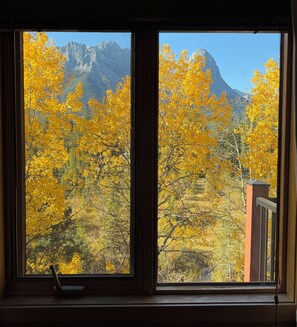 A window with a view of yellow foliage and a mountain range. - C303 Peaceful Canmore Corner- Downtown, Free parking, View, 2BR, 2BT, Sleeps 6 (Canmore)