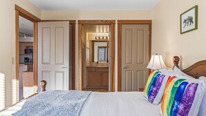 A bedroom with a bed, a nightstand, a lamp, a dresser, and a mirror. - C303 Peaceful Canmore Corner- Downtown, Free parking, View, 2BR, 2BT, Sleeps 7 (Canmore)
