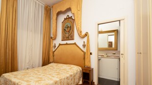 Une chambre à coucher comprenant un lit, une table de chevet, un miroir et une porte donnant sur une salle de bain.
