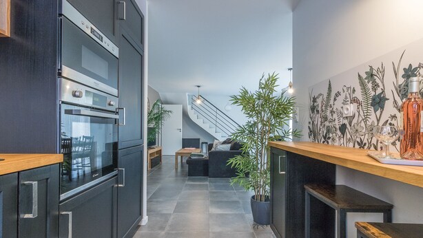 A modern kitchen with dark cabinetry, a built-in oven, and a wooden countertop.