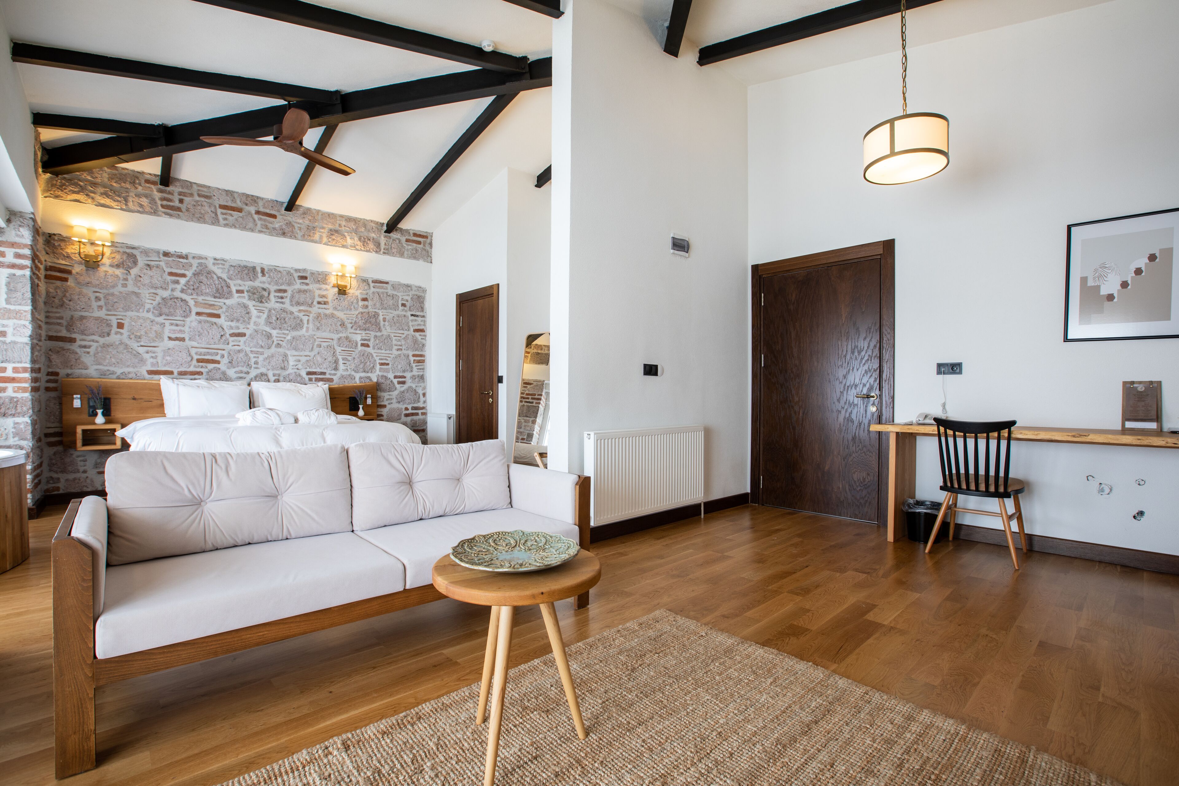 Una sala moderna con un sofá blanco, una mesa de centro de madera y una cocina con una silla de madera y una lámpara colgante.