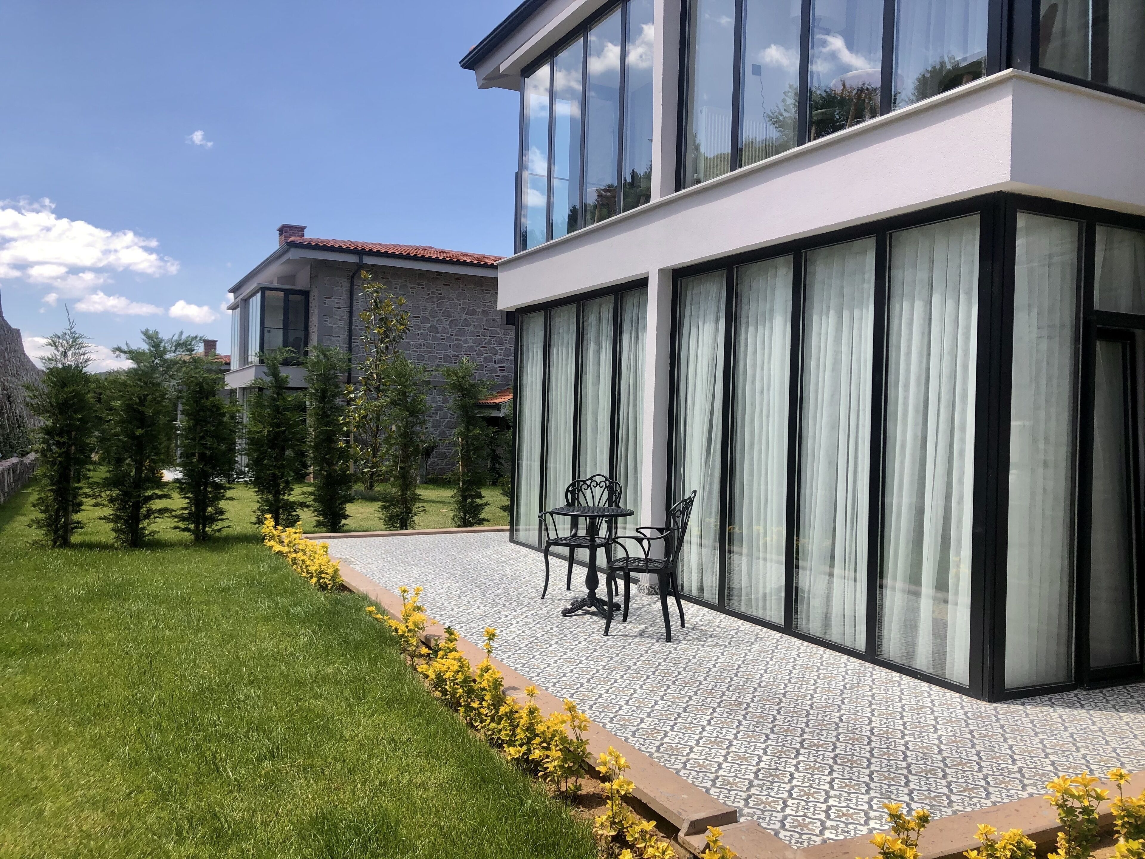 A modern house with large windows and a patio area with a table and chairs.