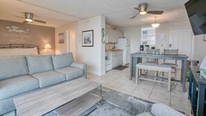 A modern living room with a grey sofa, a wooden coffee table, and a dining area with a table and chairs. - Beautiful Beach Studio at Beach And Tennis 3304 (Bonita Springs)