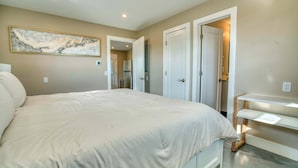 A bedroom with a large bed, a painting on the wall, and a cat tree by the door. - Mango Street Inn Suite 3 (Fort Myers Beach)