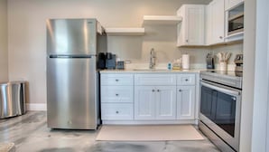 A modern kitchen with stainless steel appliances, white cabinetry, and a built-in oven. - Mango Street Inn Suite 3 (Fort Myers Beach)