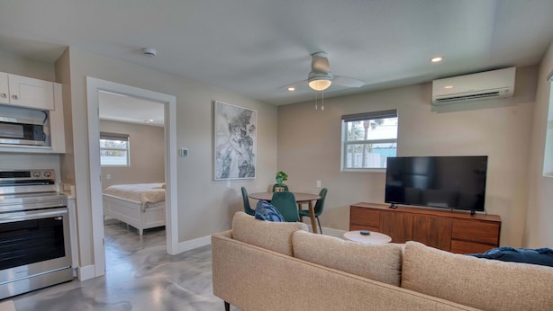 A modern living room with a sofa, TV, and dining area. - Mango Street Inn Suite 3 (Fort Myers Beach)