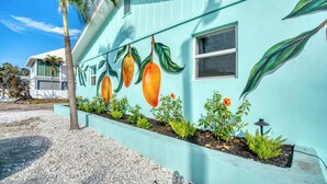 A house with a light blue exterior and a mural of mangoes and leaves. - Mango Street Inn Suite 5 (Fort Myers Beach)